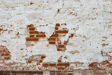 The texture of the old brick wall painted white with peeling paint