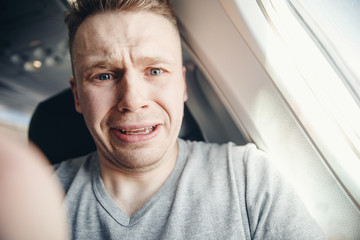 Passenger man in plane clutches his head, afraid of heights and flight. Scream and cry expression