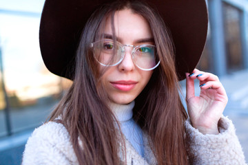 Wall Mural - Closeup portrait of young beautiful fashionable woman with sunglasses. Lady posing on dark grey background. Model wearing stylish wide-brimmed hat, jacket. Girl looking at camera. Female fashion.Toned