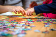 © eshana_blue - Hands of a little child and parent playing jigsaw puzzle game on a  table