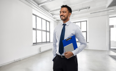 Sticker - business, realty and people concept - smiling indian businessman or realtor with clipboard over empty office room background