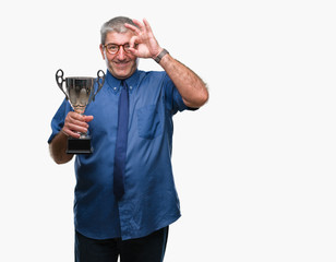 Sticker - Handsome senior successful man holding trophy over isolated background with happy face smiling doing ok sign with hand on eye looking through fingers