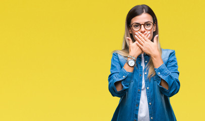 Wall Mural - Young beautiful woman over wearing glasses over isolated background shocked covering mouth with hands for mistake. Secret concept.