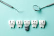Healthy white teeth and implants are smiling against green mint background and dentist tools mirror, hook.