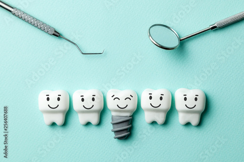 Fototapeta na szkło Zdrowe białe zęby i implanty uśmiechają się na tle zielonej mięty i lusterko dentystyczne narzędzia, hak.