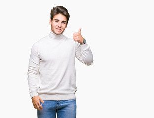 Young handsome man wearing turtleneck sweater over isolated background doing happy thumbs up gesture with hand. Approving expression looking at the camera with showing success.