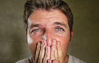 Wall Mural - head and shoulders dramatic portrait of young man crying in pain suffering depression and anxiety problem covering his mouth with the hands feeling sad and desperate