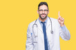 © Krakenimages.com - Handsome young doctor man over isolated background showing and pointing up with finger number one while smiling confident and happy.
