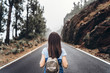 © bedya - Rear view of long hair brunette girl walking on the foggy road in the mountains