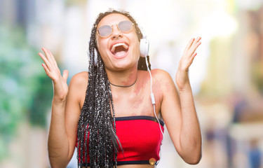 Sticker - Young braided hair african american with birth mark wearing headphones over isolated background celebrating crazy and amazed for success with arms raised and open eyes screaming excited