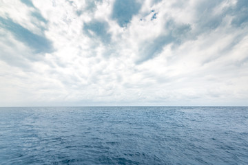 calm sea with little boats in the distance on horizon. ocean water surface with rippled waves