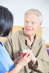 Poster - Asian nurse giving pills to aged senior man in hospital