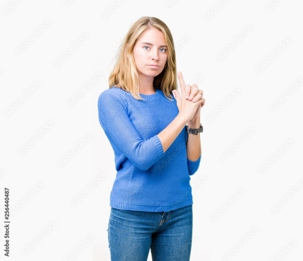 Beautiful young woman wearing blue sweater over isolated background Holding symbolic gun with hand gesture, playing killing shooting weapons, angry face