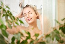 Beautiful Satisfied European Woman Washes Away Shampoo From The Head Hair In Bathroom, Takes A Shower And Enjoys, Smiling