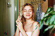 © amixstudio - The girl after shower holds in hand soft, saturated, smooth and silky hair with a satisfied facial expression, smiling with eyes closed in pleasure in the bathroom
