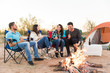 © AntonioDiaz - Group of friends having fun while sitting by campfire and roasting food
