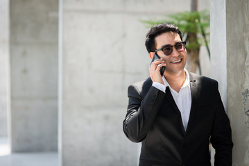 Handsome Asian businessman using smart phone outdoor.