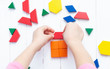 A child plays with colored blocks constructs a model on a light wooden background