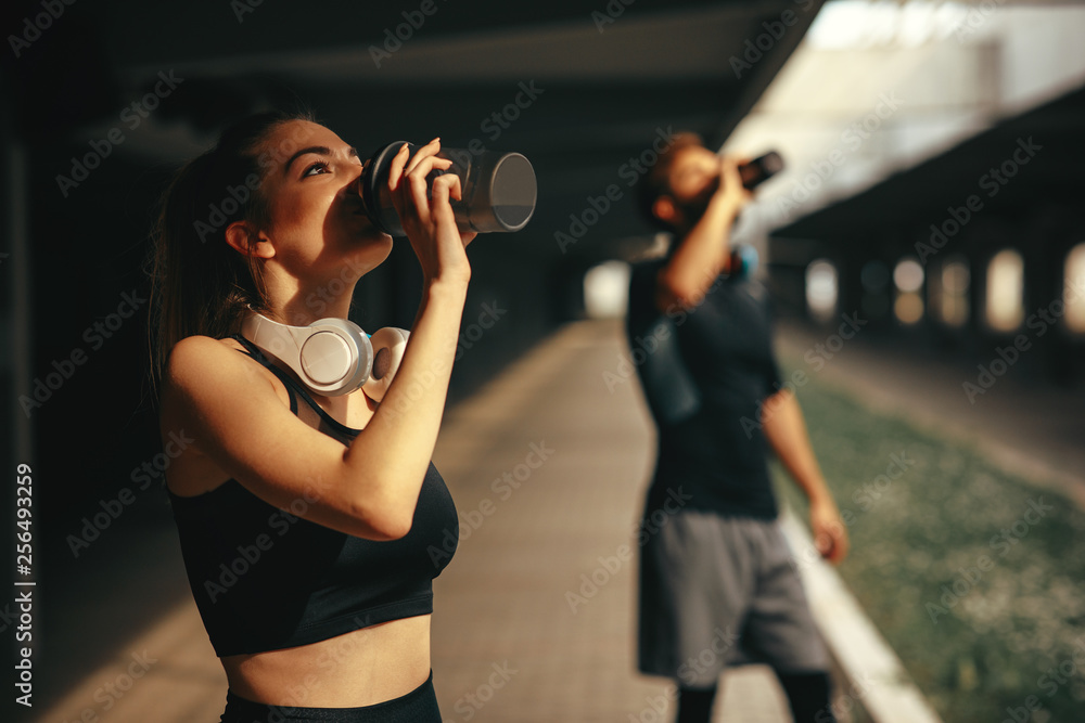Young woman and man drinking protein shake after workout - obrazy, fototapety, plakaty 
