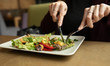 Close up attractive woman hand holding fork and spoon to eating vegetable salad at lunch in cafe 