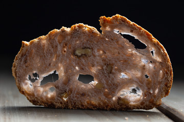 A slice of rustic bread backlighted on a dark background