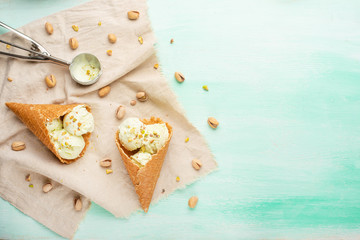 Wall Mural - pistachio ice cream cones with pistachios and a spoon for ice cream. On a mint background.Flat lay