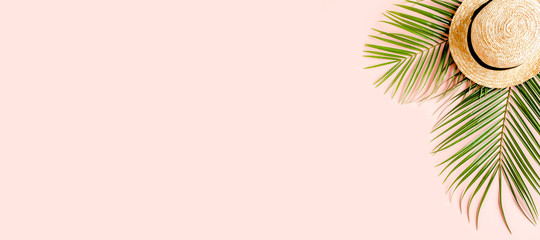 Tropical palm leaves and hat on pink background with more space for text. Flat lay, top view minimal concept.