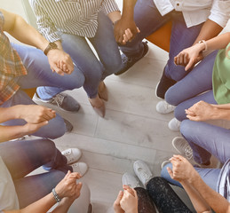 Wall Mural - People putting hands together indoors, top view. Unity concept