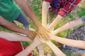 Group of volunteers putting hands together outdoors, top view