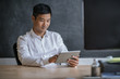 © mavoimages - Smiling Asian businessman working on a tablet in an office