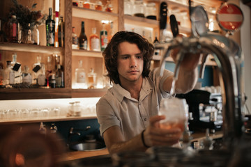 Wall Mural - Bartender preparing drinks behind a bar counter at night