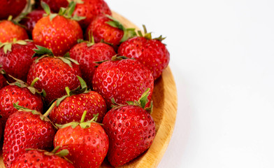 Strawberrys many with both ripe fruit and  not fruit ripe in wooden tray Strawberrys and wooden tray all laid are on a white background.