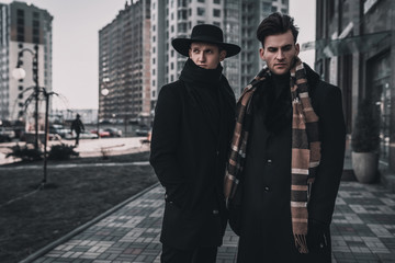 Wall Mural - Two young stylish men posing on city street. Classic urban style. Street man model tests.