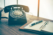 © totojang1977 - Ball point pen on notebook with old black phone background, retro style concept
