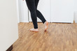 © contrastwerkstatt - Barefoot young woman walking across a wooden floor