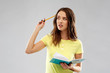 © Syda Productions - education, school, inspiration and people concept - young woman or teenage student girl in yellow t-shirt with diary or notebook and pencil thinking hard over grey background