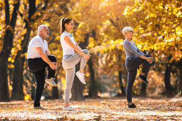 Senior man and woman and young female instructor  workout on fresh air. Outdoor activities, healthy lifestyle, strong bodies, fit figures. Stylish, modern sportswear. Different generations