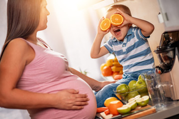 Canvas Print - Mother and her kid making fresh orange juice in kitchen