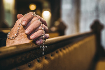 Praying hands with rosary in church