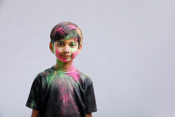 Indian little boy playing with the color and giving multiple expressions in holi festival 