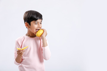 Cute indian/Asian little boy eating Mango with multiple expressions. isolated over white background