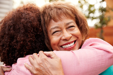 Wall Mural - Senior black mum and her middle aged daughter embracing outdoors, close up