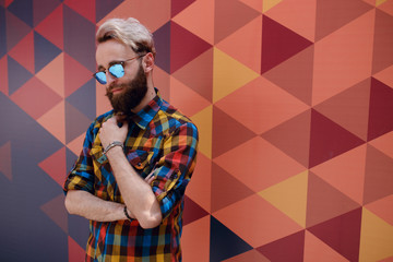 Handsome portrait of a young hipster man, posing near multicolore background, dressed in colorful shirt.