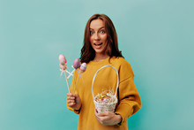 Studio Portrait Of Charming Brunette Woman With Curly Hair Wearing Yellow Pullover Posing With Basket With Easter Eggs