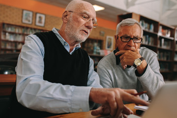 Wall Mural - Senior men discussing subject sitting in a library