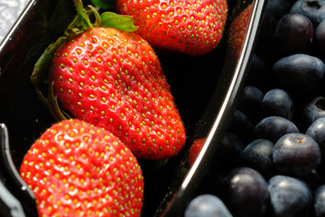 plastic containers box of berries, red currants, blueberries, and strawberries. Close up