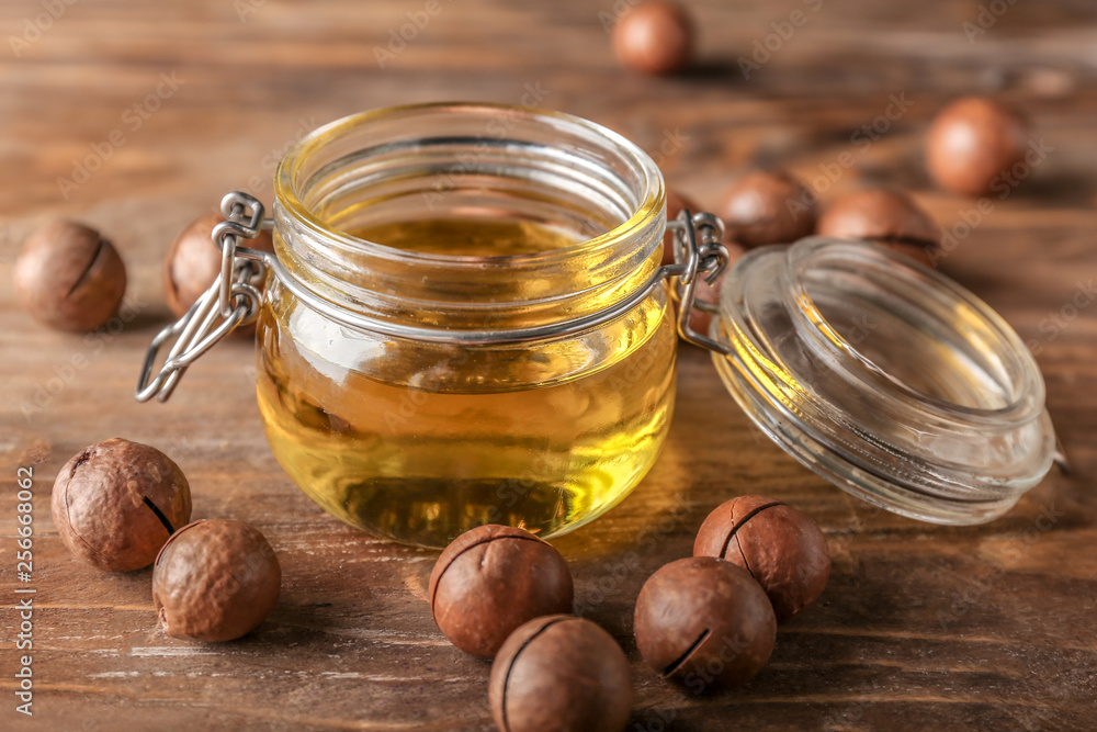 Oil with macadamia nuts on wooden table