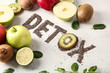 Word DETOX with fresh fruits on light background