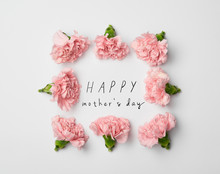 Top View Of Floral Frame Made Of Pink Carnations On White Background With Happy Mothers Day Lettering