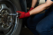 Hands Of Technician Using A Torque Wrench To Remove Car Wheel Bolts - Low View Of A Auto Repair Mechanic Operating Hand Tools To Secure Wheel And Tire In A Garage